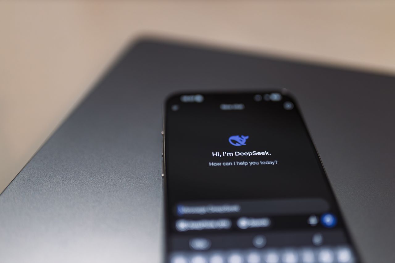 Home Close-up of a smartphone with AI assistant interface on screen over a laptop.