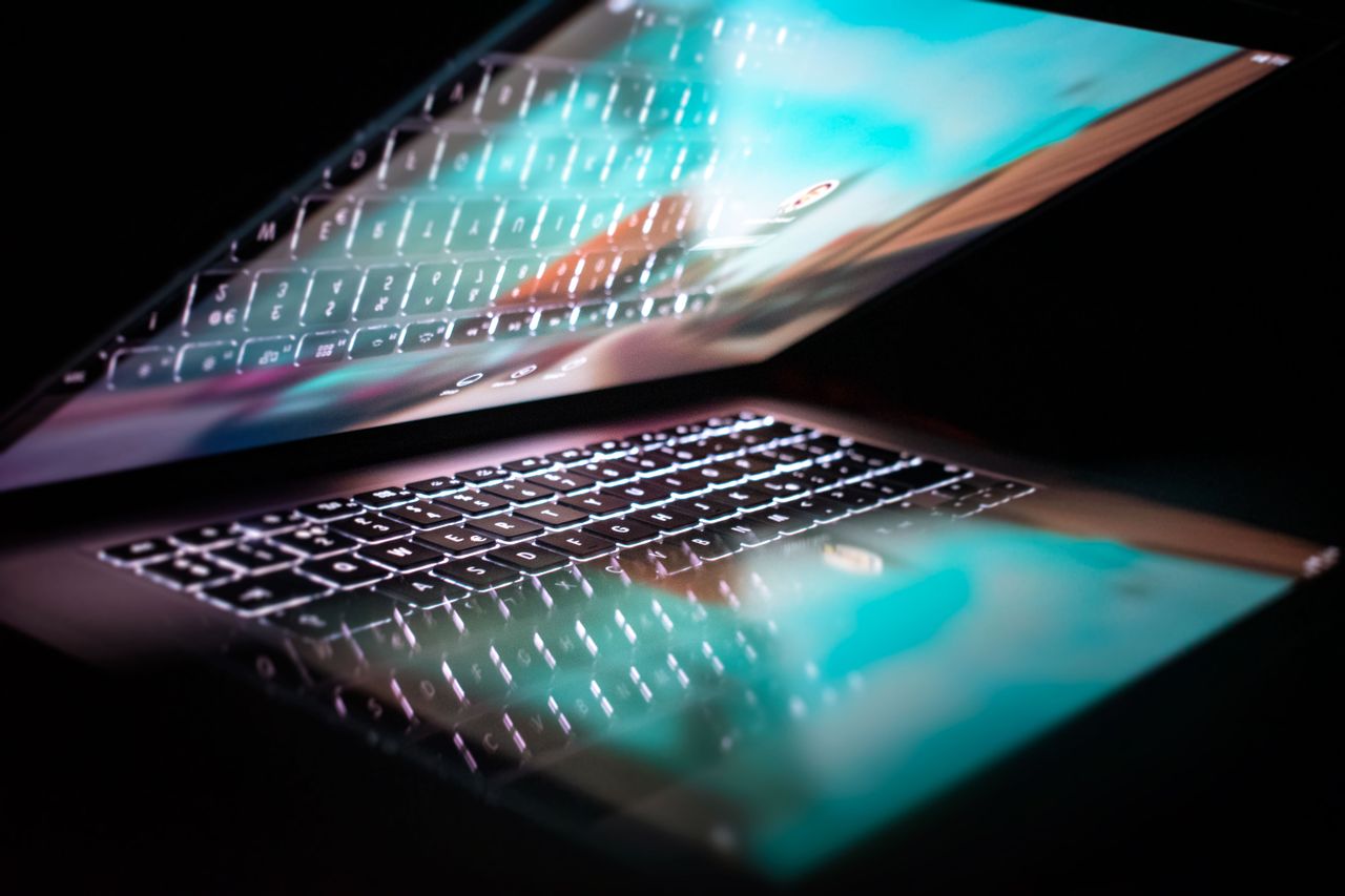 Home Close-up of a modern laptop with illuminated keyboard and colorful screen reflection.